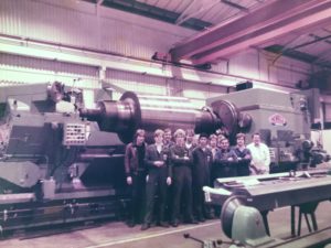 Foreman Vic Markley with apprentices in front of Roll Grinder